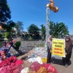 Volunteers clean piles of plastic waste in Kali Tebu River using nets and a floating platform, with a giant faucet installation made from plastic bottles and a “Kali Tebu is Not a Dumping Site” sign on the riverbank.