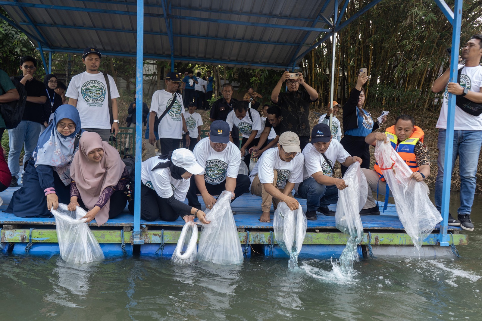 Peserta menebarkan benih ikan lokal ke Kali Surabaya dari atas perahu